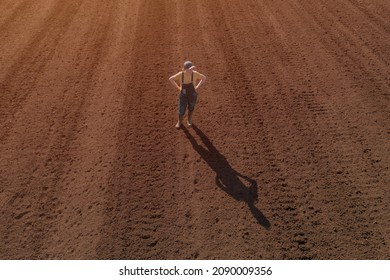 Confident satisfied female farmer standing on ploughed field, drone pov high angle view, copy space included