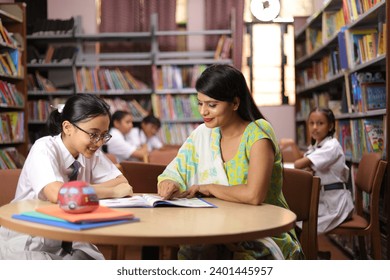 Confident school teacher teaching girl child student in library, extra classes, education, reading book, hard work, study. Dedicated Student. - Powered by Shutterstock