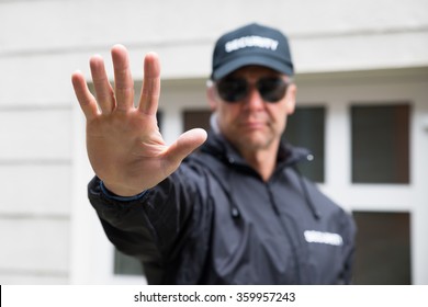 Confident Security Guard Making Stop Gesture Outside Building