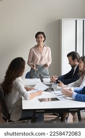Confident senior corporate coach woman giving seminar to business team. Female director, box, CEO talking with employees on office meeting, discussing project, instructing. Vertical shot - Shutterstock ID 2258472083