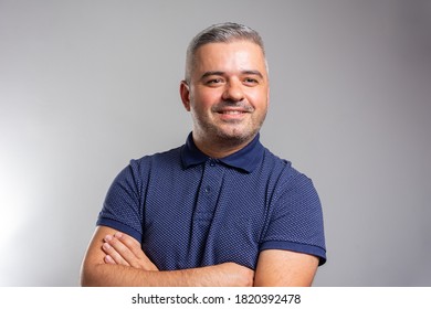 Confident senior man in blue t-shirt crossing hands on chest and looking at camera while standing against gray background. Self confident caucasian senior. - Shutterstock ID 1820392478