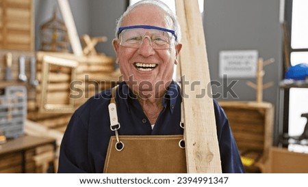 Confident senior man, a professional carpenter, smiling while securely holding a wood plank in carpentry workshop