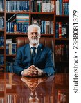 Confident senior university rector posing in a library filled with books. Experienced and successful, this mature Caucasian man is the academic leader of the prestigious college.