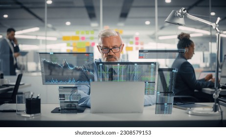 Confident Senior Venture Capital Director Using Laptop Computer in Office with Colleagues. Experienced Trader Searches Market Opportunities. VFX Hologram Edit Visualizing Stock Exchange Interface. - Powered by Shutterstock