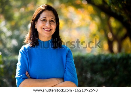 Confident senior woman with arms crossed at park