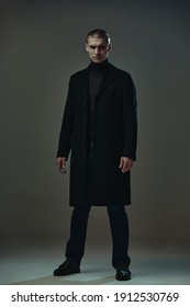 Confident Serious Angry Guy In Black Coat, Detective Or Security On Gray Studio Background, Full-length Male Portrait