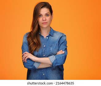 Confident Serious Woman In Blue Denim Shirt Standing With Arms Crossed Over Orange Background.