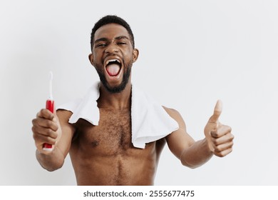 Confident shirtless man holding a toothbrush and giving a thumbs up, promoting good dental hygiene and selfcare - Powered by Shutterstock