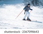 Confident skier skiing downhill in high mountains. Handsome, fashionable man in full sports equipment being photographed in movement on ski slope. Experienced male skier skiing in the mountains.