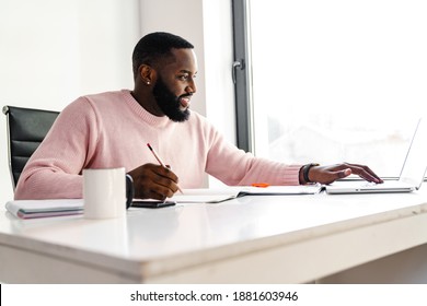 Confident smiling attractive young african businessman working in the office, using laptop computer - Shutterstock ID 1881603946