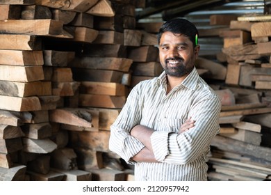 Confident smiling carpenter with arms crossed standing by looking at camera - concept of self confidence, skilled professional occupation and successful worker