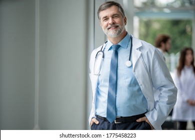 Confident Smiling Doctor Posing In The Hospital With Medical Team Working On The Background