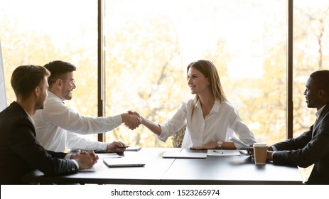 Confident smiling female company owner executive manager shaking hands with corporate clients after successful negotiations. Happy woman representative welcoming investors at office business meeting.