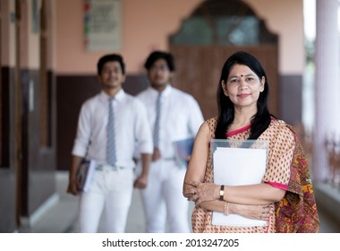 Confident Smiling Indian School Teacher With Students In Background