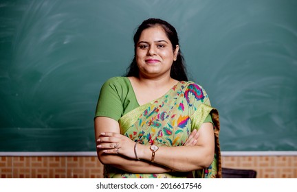 Confident smiling Indian school teacher standing in front of the blackboard in classroom , copy space - Shutterstock ID 2016617546