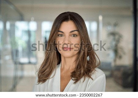 Confident smiling Latin professional mid aged elegant business woman corporate leader, happy beautiful mature female executive, lady manager standing in office looking at camera, headshot portrait.