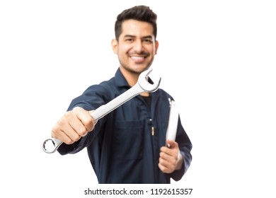 Confident and smiling male mechanic showing wrench against white background - Shutterstock ID 1192615357