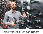 Confident smiling salesman on foreground in power tools store.
