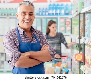 Confident smiling supermarket clerk posing at the shopping mall, retail job concept