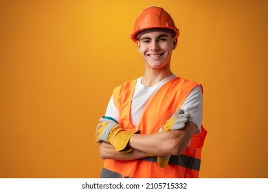 Confident smiling teen boy wearing orange hard hat against yellow background - Powered by Shutterstock