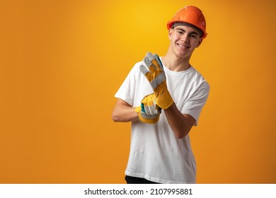 Confident Smiling Teen Boy Wearing Orange Hard Hat Against Yellow Background