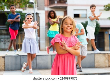 Confident smiling tween girl street dancer posing during performance with group in summer city ..