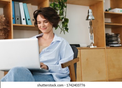 Confident smiling young attractive woman entrepreneur sitting on the chair in the office, working on laptop computer - Shutterstock ID 1742403776