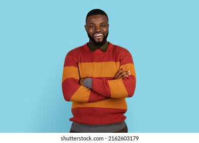 Confident Smiling Young Black Man Standing With Folded Arms Over Blue Background, Cheerful Millennial African American Male With Crossed Hands Posing In Studio, Looking At Camera, Copy Space