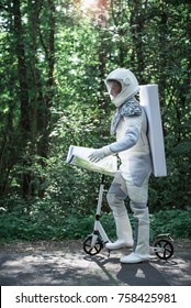 Confident spaceman wearing white armor is standing near scooter and holding map. He looking forward. Profile