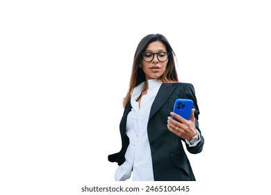 Confident Spanish young businesswoman in suit holds phone reading message against huge buildings. Puzzled later received news from client. Successful entrepreneur looks at phones screen