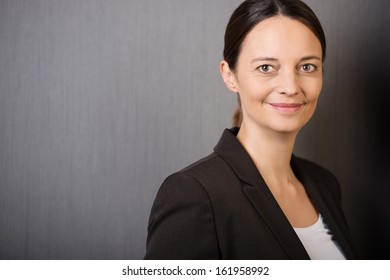 Confident Stylish Businesswoman With A Warm Friendly Smile, Head And Shoulders Portrait On Grey