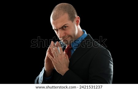 Confident and stylish caucasian businessman in a dapper suit smiling and plotting a cunning strategy for corporate success against a black background portrait
