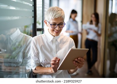 Confident stylish european mature business woman standing at workplace.
