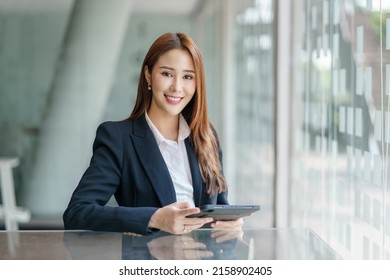 Confident successful Asian business woman sitting smiling looking at camera in office. - Shutterstock ID 2158902405