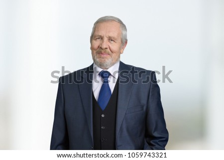 Confident successful businessman portrait. Old senior grandpa in business suit with tie. Bright blurred background.
