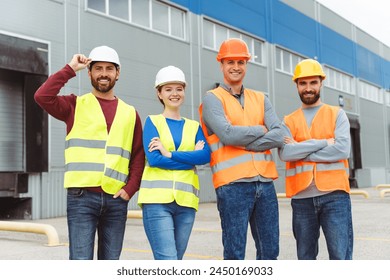 Confident successful managers, workers, men and woman wearing hard hats, vests and work clothes with crossed arms standing outside warehouse, looking at camera. Business concept, teamwork - Powered by Shutterstock