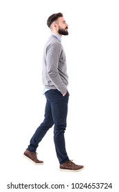 Confident successful smart casual businessman walking with hands in pockets. Full body length portrait isolated on white studio background.