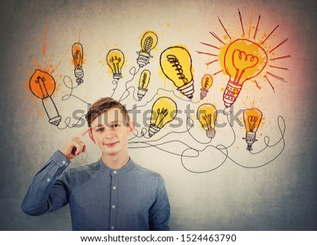Confident teenage boy pointing forefinger to head showing where genius ideas come from, and shining light bulbs sketches like different thoughts. Genius creativity concept, planning way to success.