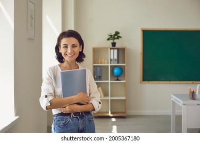 Confident Toothy Smiling Caucasian Female Teacher Holding Digital Tablet Stand In Classroom. Half-length Portrait. Elementary Or Highschool Education, Learning And Teaching Concept. Back To School