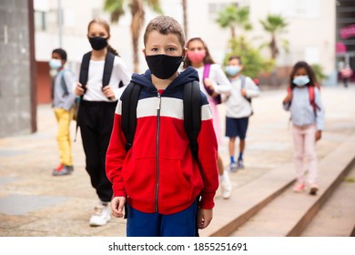 Confident Tweenager In Protective Mask Walking With Other Schoolchildren To School Campus After Lessons On Spring Day. Concept Of Necessary Precautions In COVID Pandemic