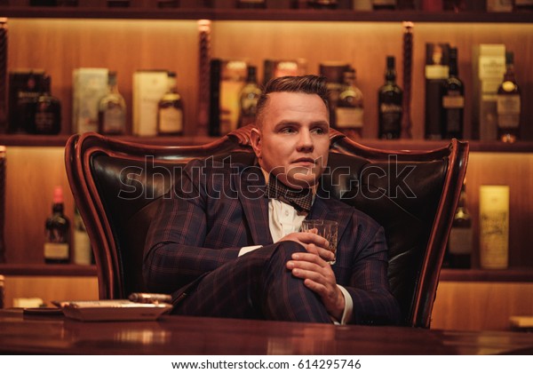 Confident upper class man with glass of beverage in\
gentlemen\'s club