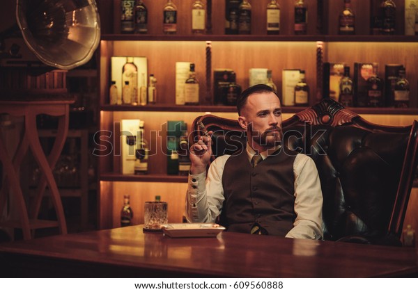 Confident upper class man smoking cigar in\
gentlemen\'s club