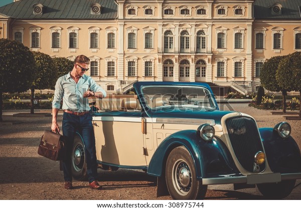 Confident wealthy young man with briefcase near classic\
convertible 