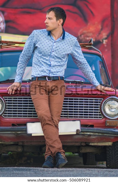 Confident wealthy\
young man near old red\
car