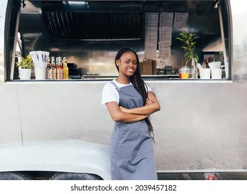 Confident woman in apron standing at her food truck with crossed arms - Powered by Shutterstock