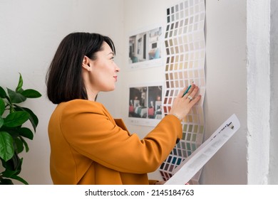 Confident Woman Architect Choosing Color Swatches For  Interior Renovation. Interior Designer Looking On Samples Of Wall Paint. Architecture And Interior Design Concept.