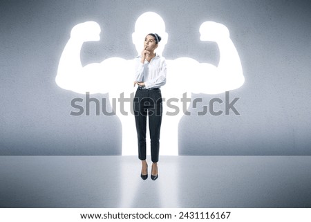 A confident woman in business attire stands with a muscular shadow on the wall, symbolizing strength and empowerment