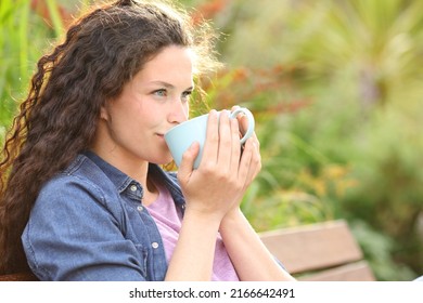 Confident woman drinking coffee looking away sitting in a bench in a park - Powered by Shutterstock