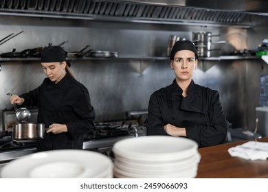 Confident woman executive chef standing in restaurant kitchen, posing on camera, while his team working - Powered by Shutterstock