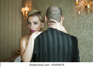 Confident Woman Hugging A Man Standing With His Back To The Camera